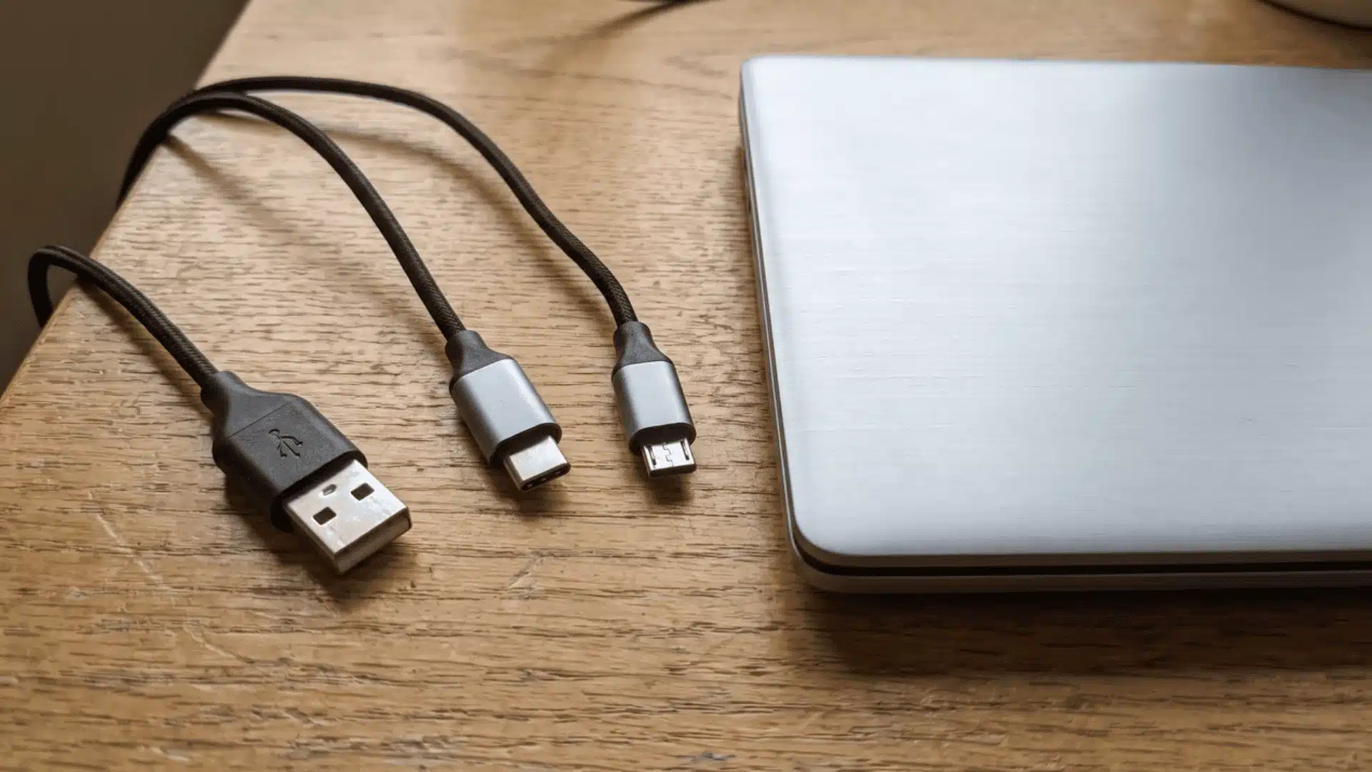 USB-A, USB-C, and Micro-USB cable ends arranged beside a laptop