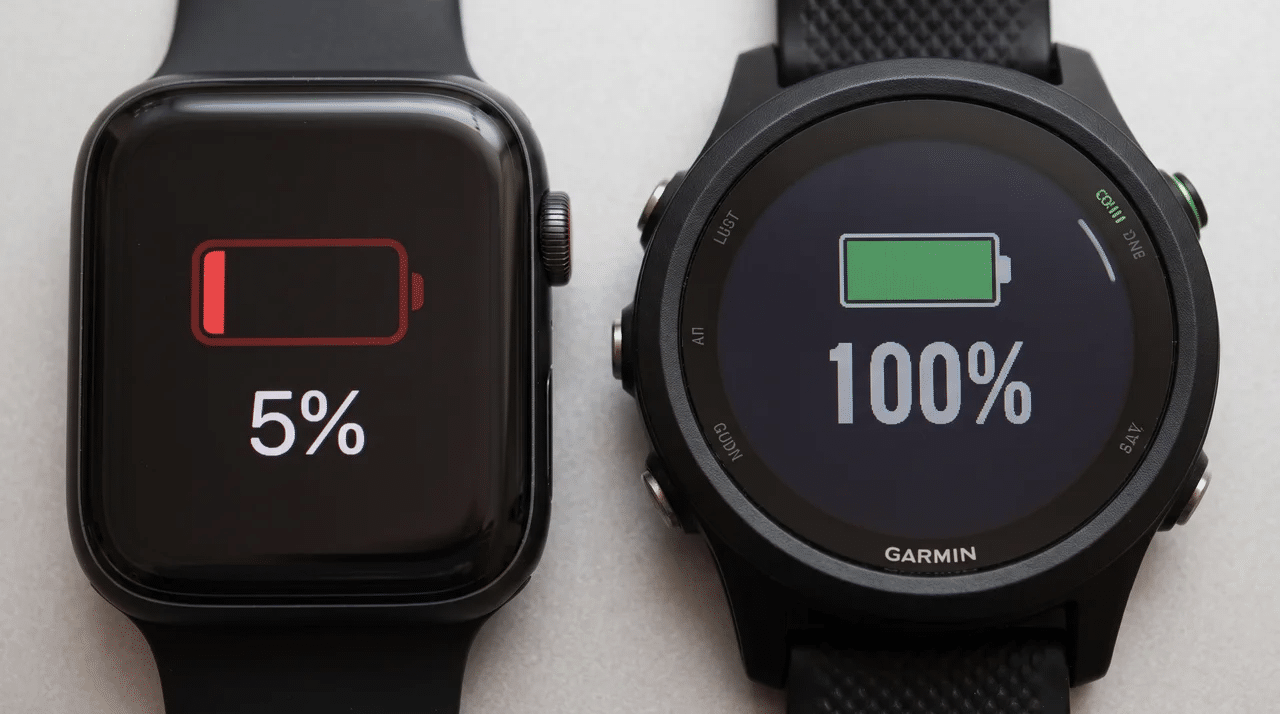 Apple Watch showing low battery beside a Garmin watch showing full battery.