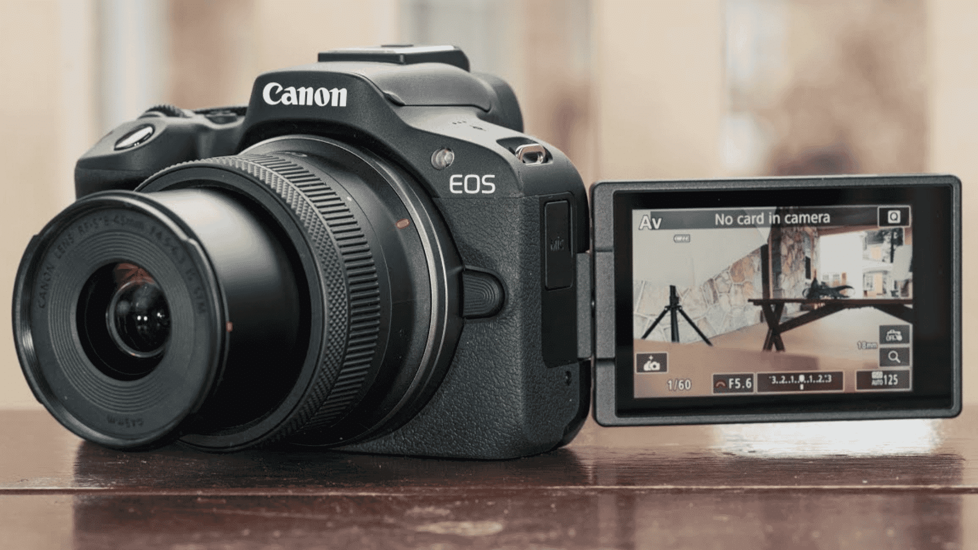 Black Canon EOS camera with an extended lens and an open flip-out screen displaying camera settings and