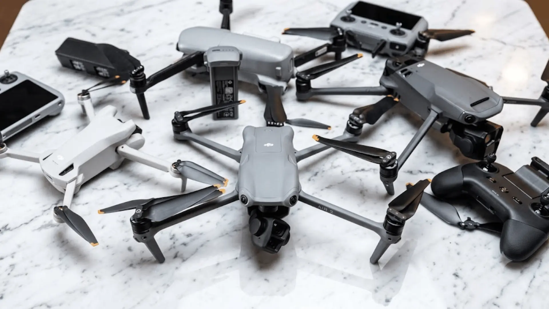 Multiple camera drones and remote controllers arranged on a white marble table