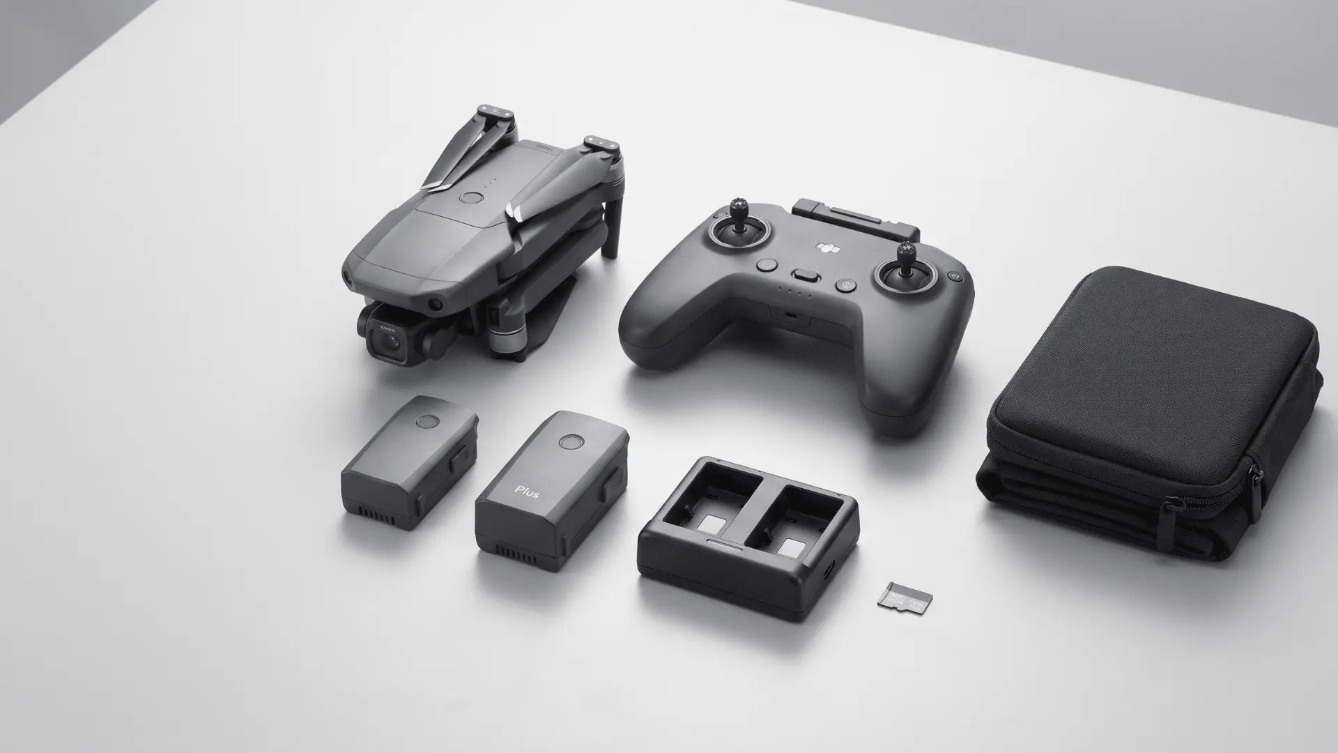Compact camera drone with its controller, batteries, charging hub, memory card, and carrying case.