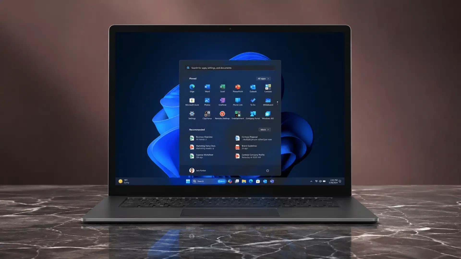 Laptop displaying the Windows 11 Start menu on a polished marble table