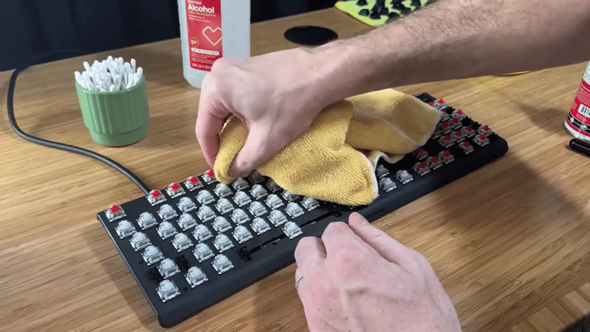 Mechanical keyboard being cleaned with a microfiber cloth after keycap removal on a desk
