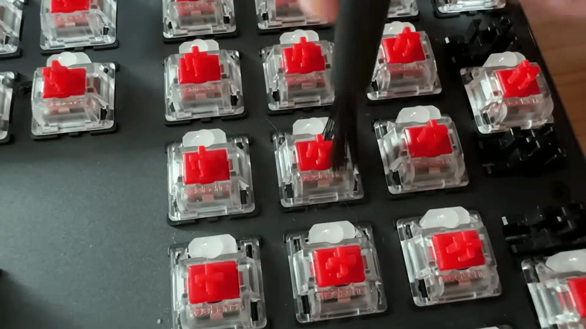 Mechanical keyboard switches being cleaned with a brush after keycap removal