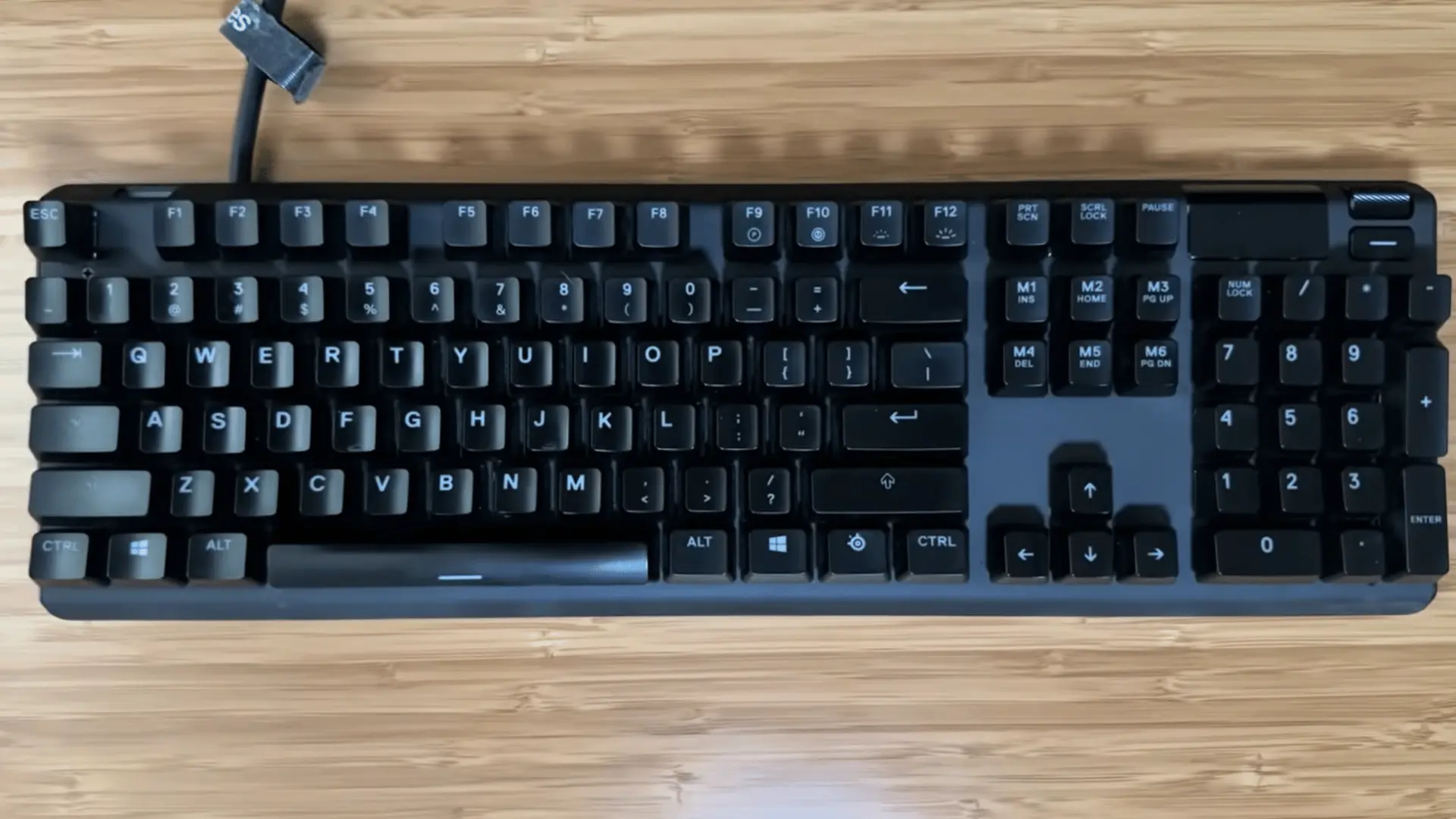 Mechanical keyboard with black keycaps arranged on a wooden desk surface