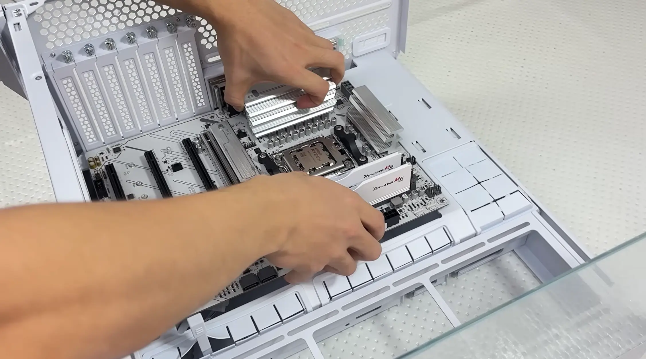 Motherboard being positioned inside a white PC case during the installation process.