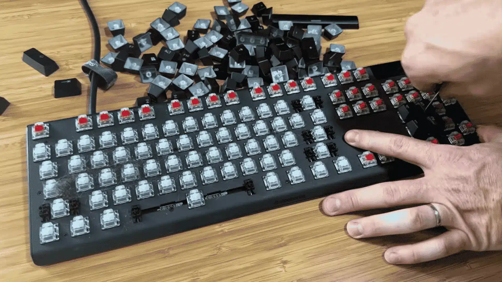 Person removing keycaps from a mechanical keyboard for deep cleaning on a wooden desk