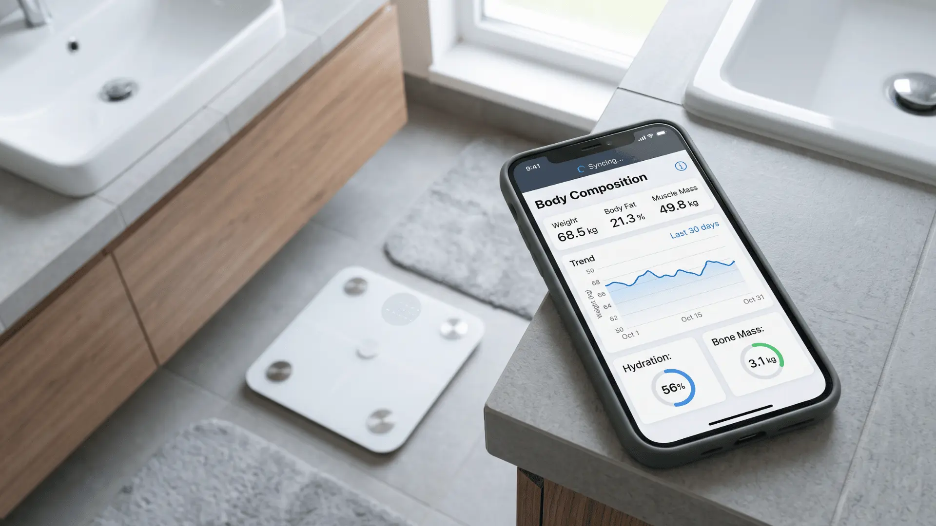Smartphone showing body composition measurements and progress charts beside a connected smart scale.