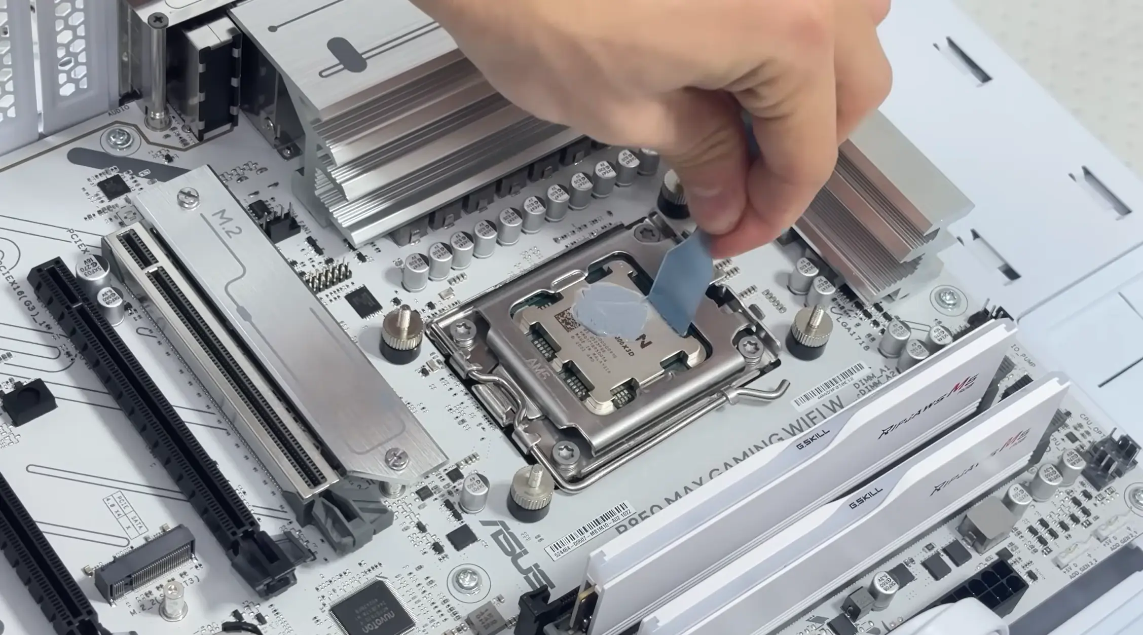 Thermal paste being spread across a CPU installed on a motherboard before mounting the CPU cooler.