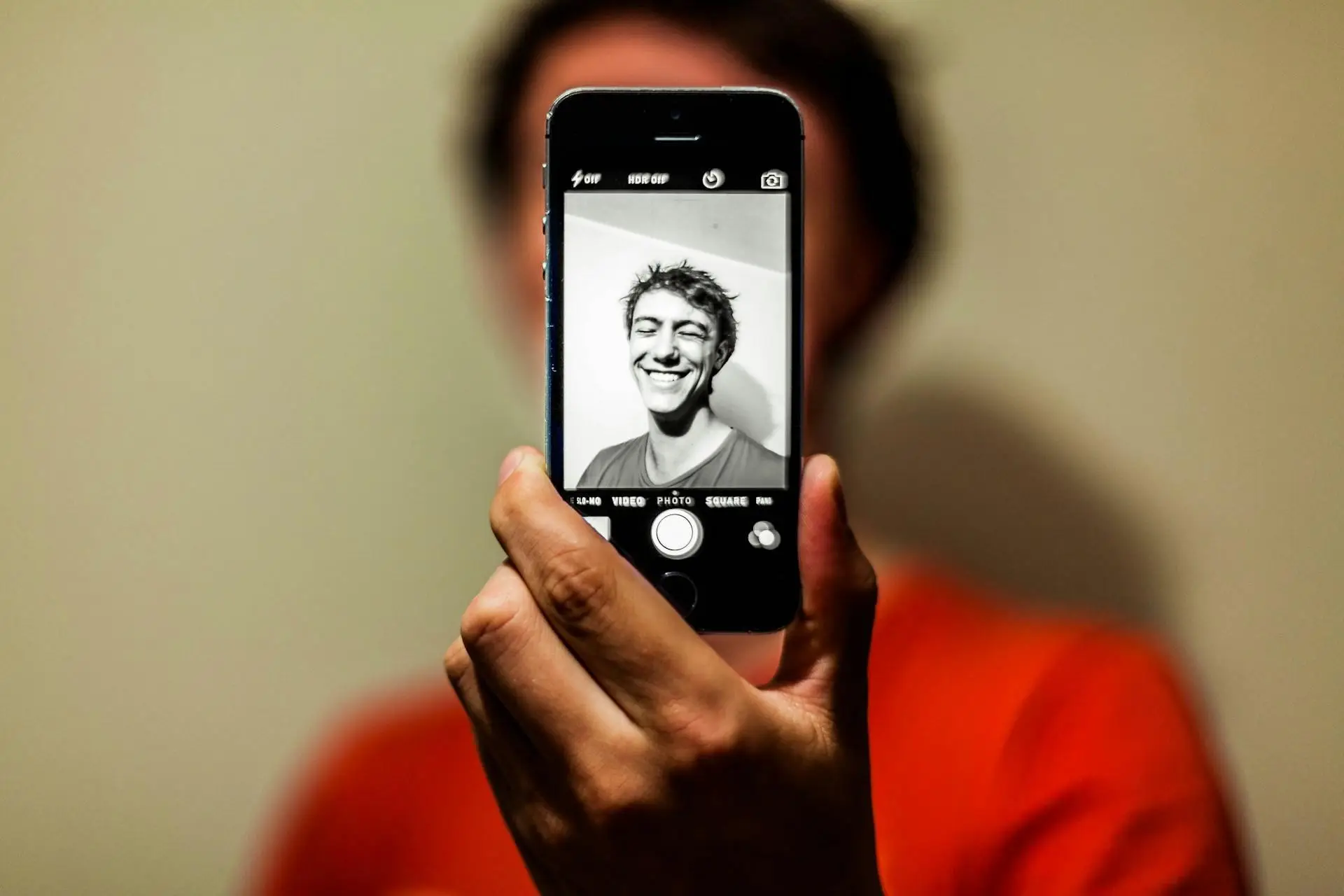 Close-up of a hand holding a smartphone with a black and white smiling selfie