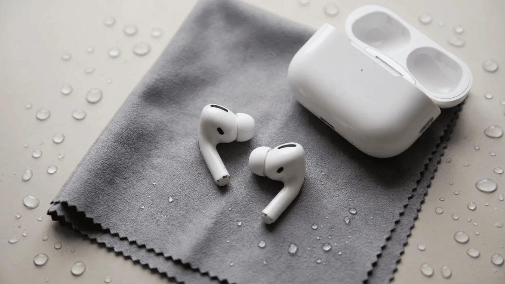 AirPods Pro drying on a microfiber cloth with water droplets nearby.