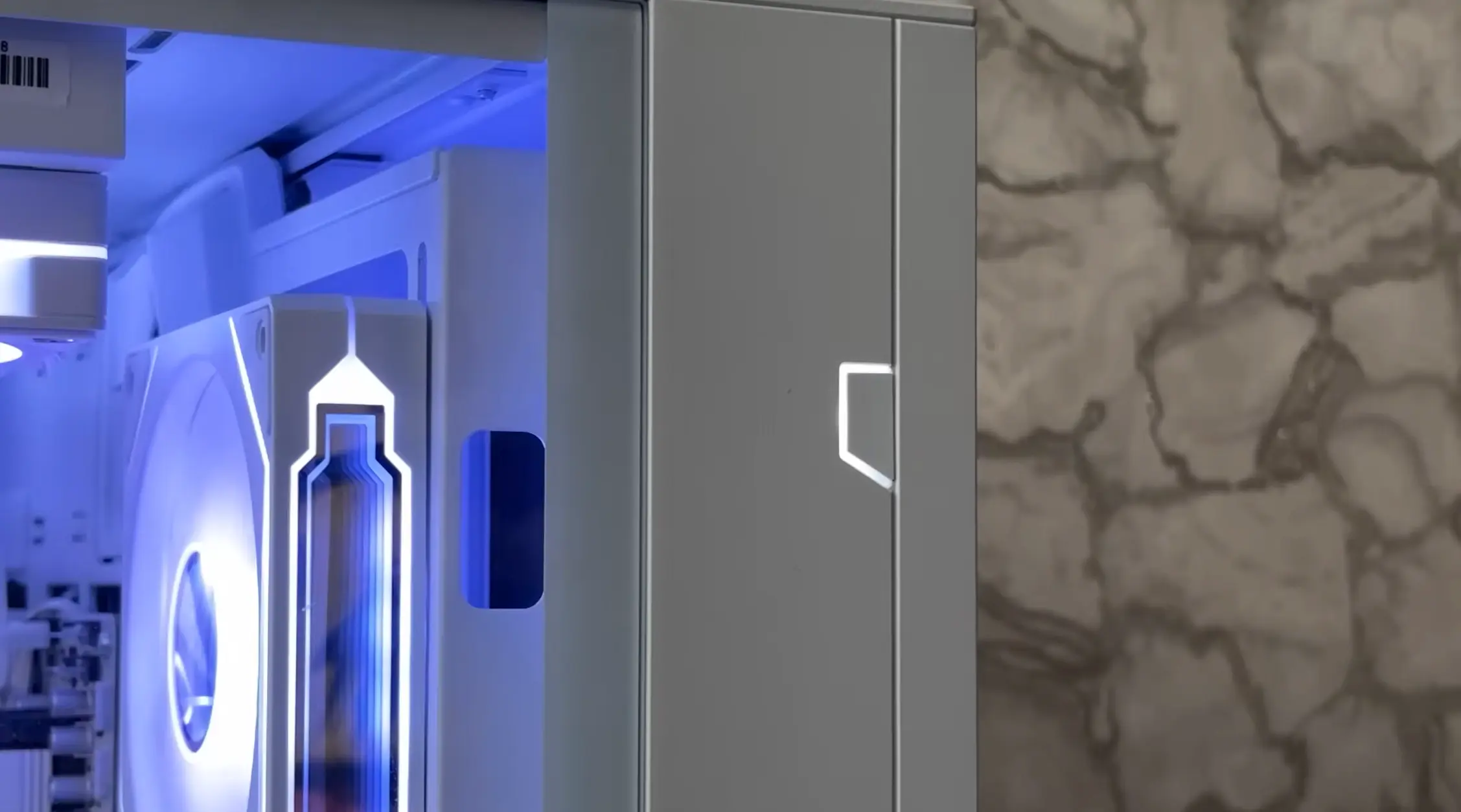 White PC case with installed cooling fans and illuminated RGB lighting during the build process.