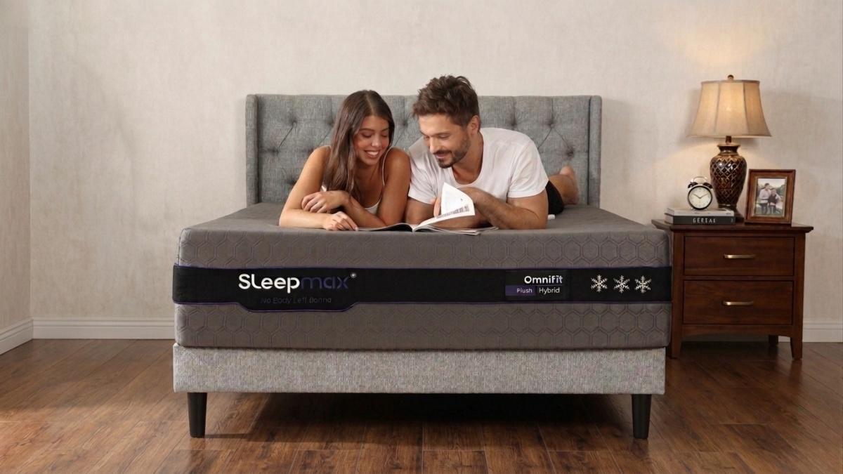 Couple reading book on gray upholstered bed in cozy bedroom with wooden floor and bedside lamp