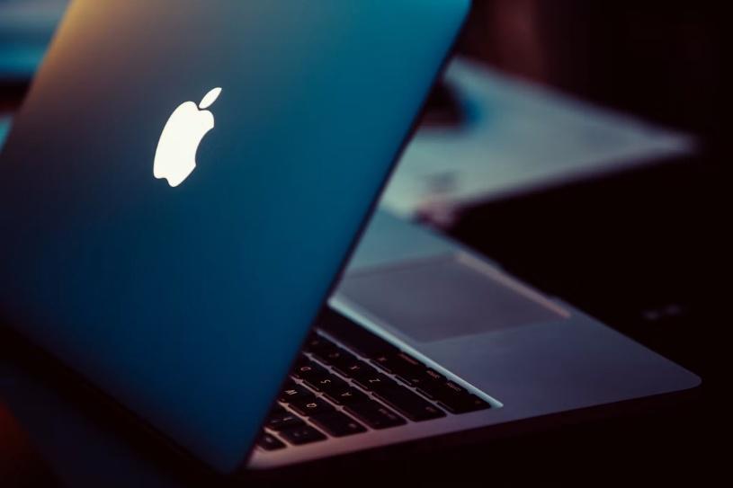 Laptop with glowing logo partially open in dimly lit room