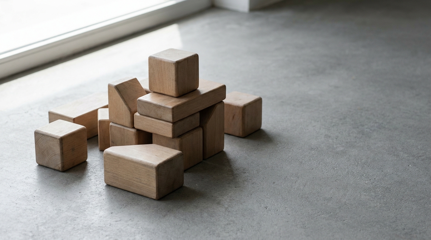 Wooden building blocks stacked on concrete floor near large window