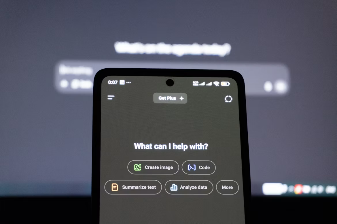 Smartphone screen displaying app interface with blurred text on computer monitor in the background